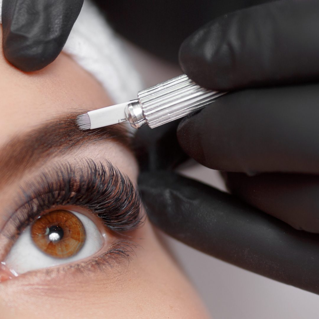 Permanent makeup eyebrows. Mikcobleyding eyebrows workflow in Cloud 9 salon. Cosmetologist applying a special permanent makeup on a woman's eyebrows.